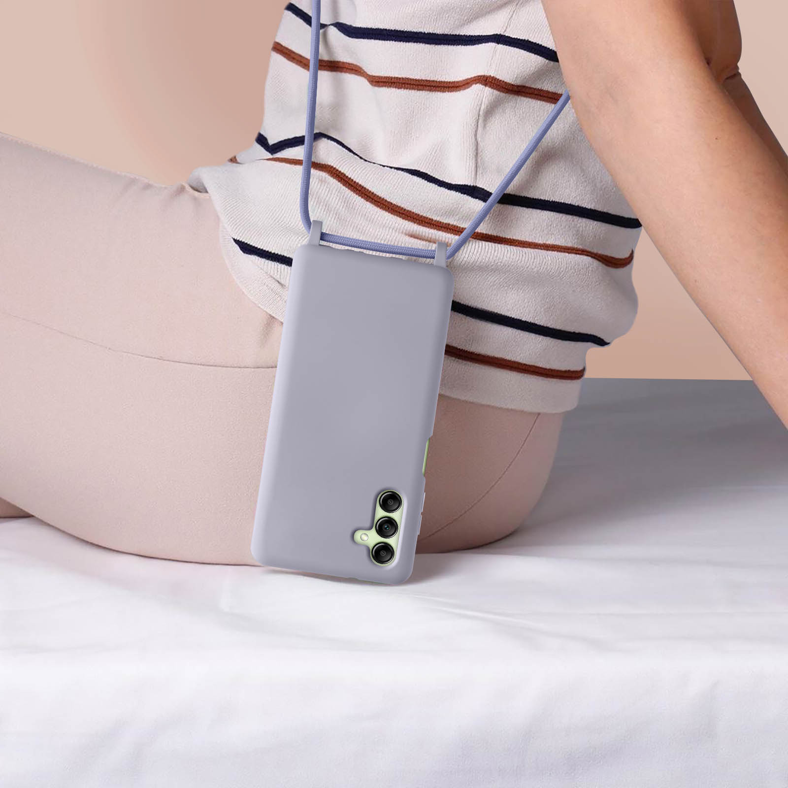 Donna con custodia viola per telefono e cordino, seduta su un lenzuolo bianco. Primo piano.