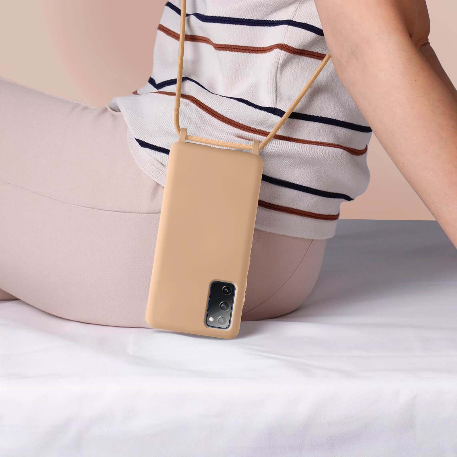 Persona seduta, che tiene un telefono con cinturino. Il telefono è color beige.