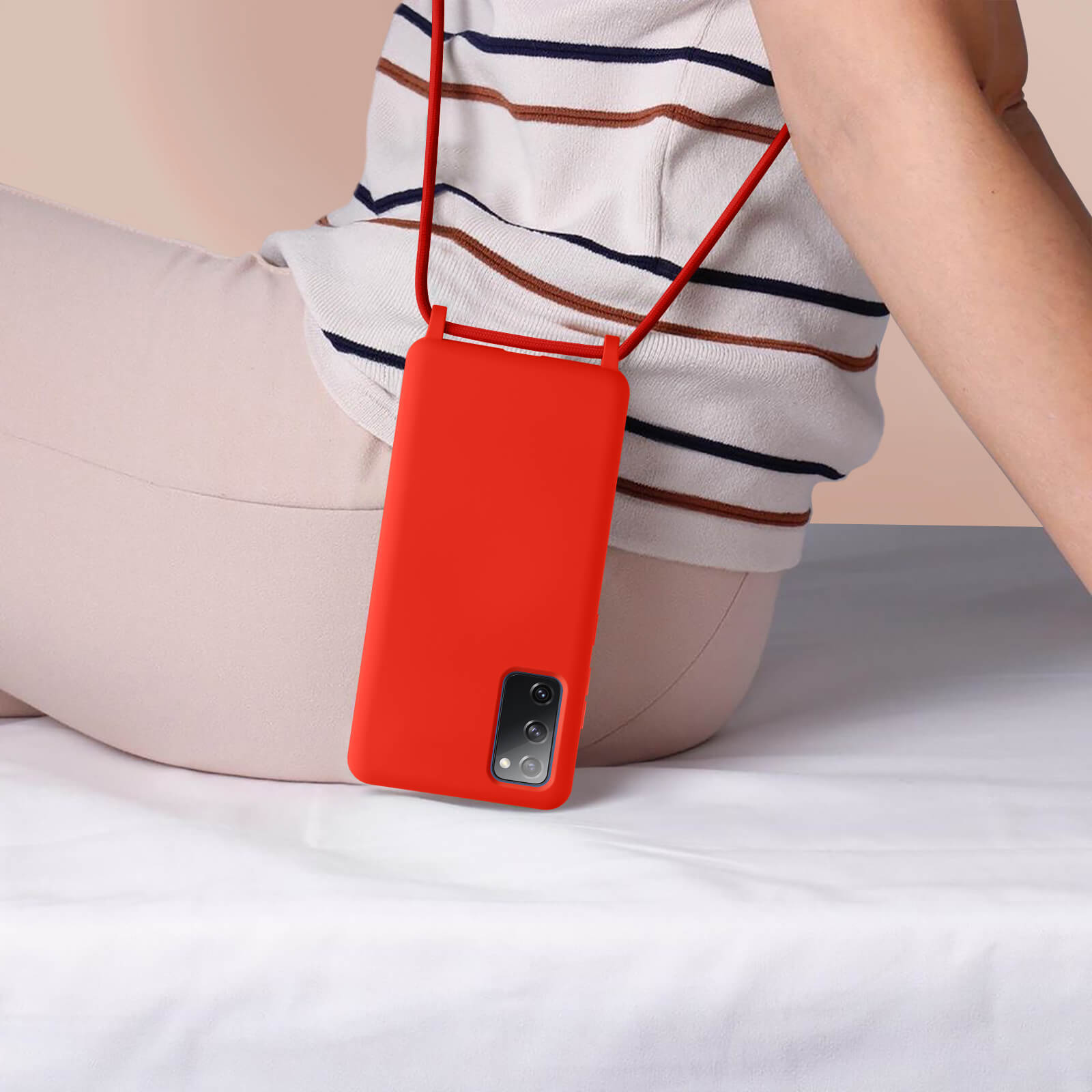 Personne avec un étui de téléphone rouge suspendu à un cordon rouge. Chemise blanche et pantalon beige.
