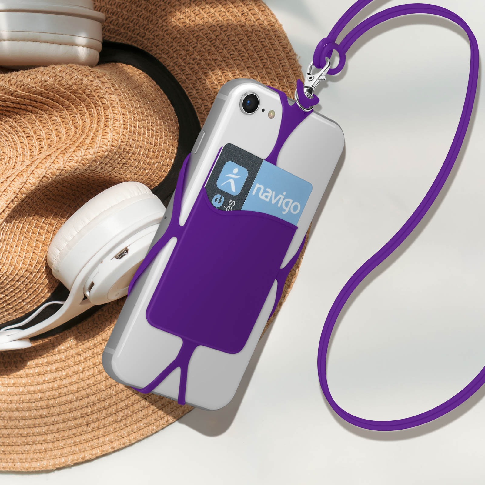 Telefono in custodia con cordino viola con carte. Un cappello e delle cuffie sullo sfondo.