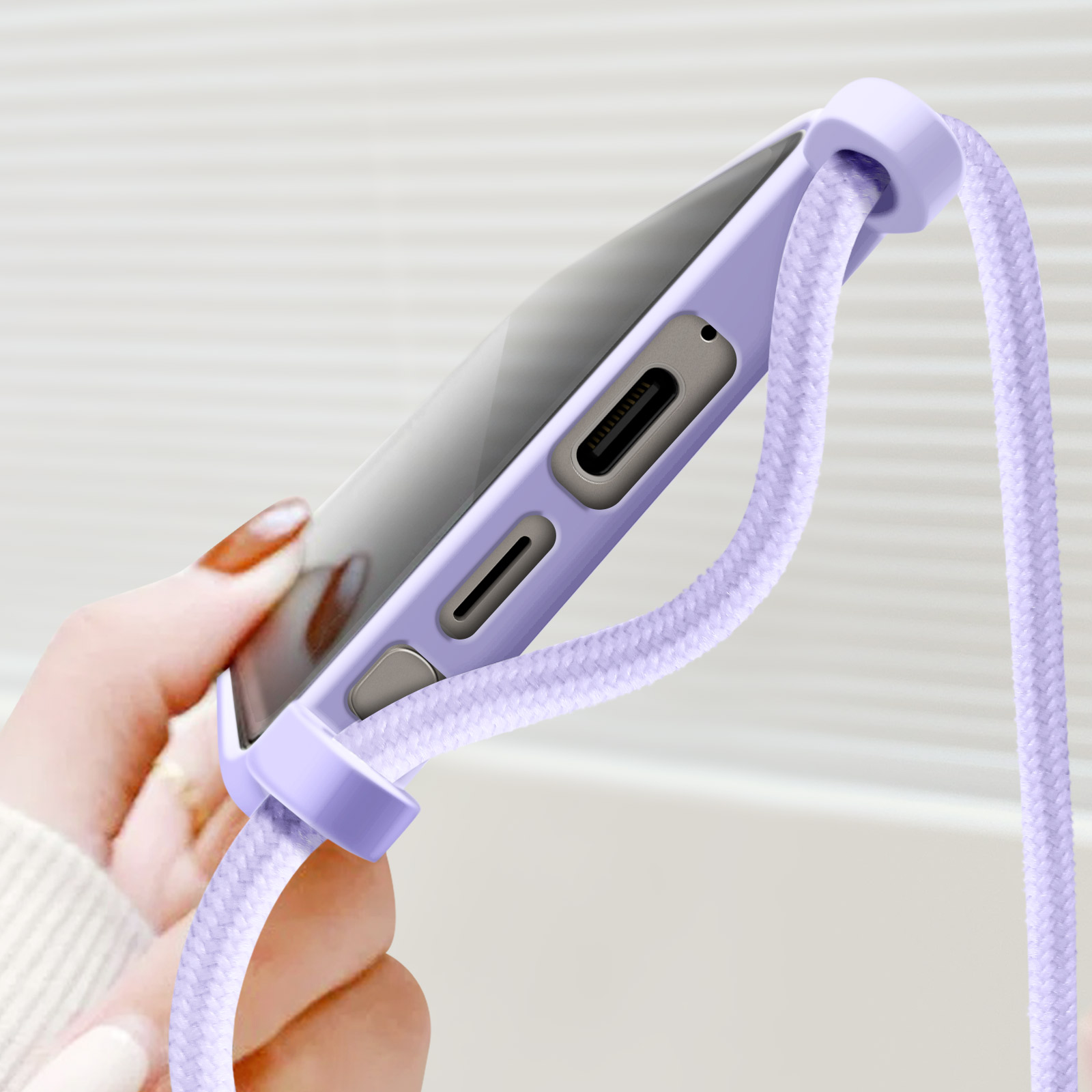 Una custodia viola con un cordino. Una mano tiene il telefono, vista ravvicinata.