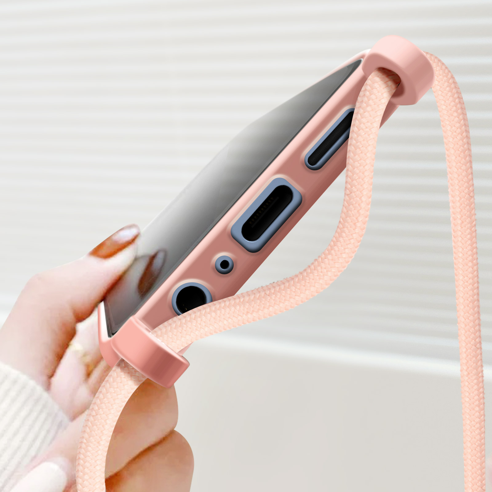 Una mano che tiene un telefono in una custodia rosa con un cinturino rosa.