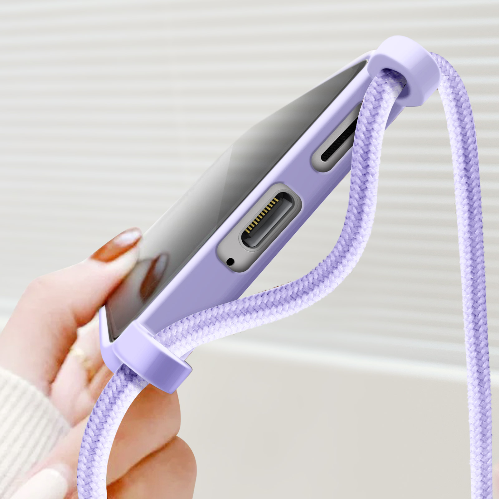 Una mano che tiene una custodia viola con un cinturino viola. Sfondo bianco.