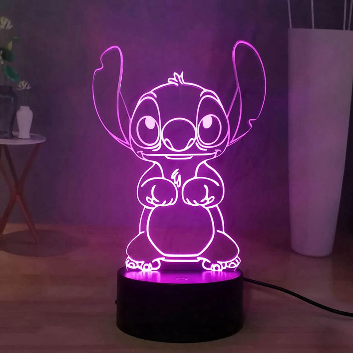 Stitch aus Lilo & Stitch, rosa beleuchtet. Die Figur steht auf einem schwarzen Sockel auf einer Holzoberfläche.