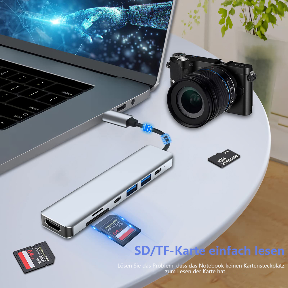 Ein Laptop, ein USB-Hub, SD-Karten und eine Kamera auf einem Tisch.