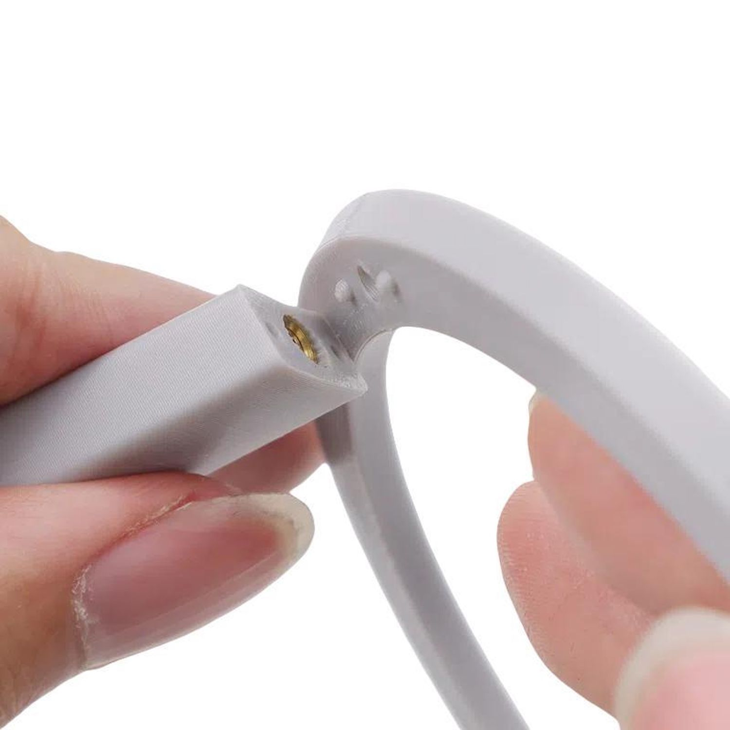 Due mani uniscono due parti di un dispositivo di plastica grigia.