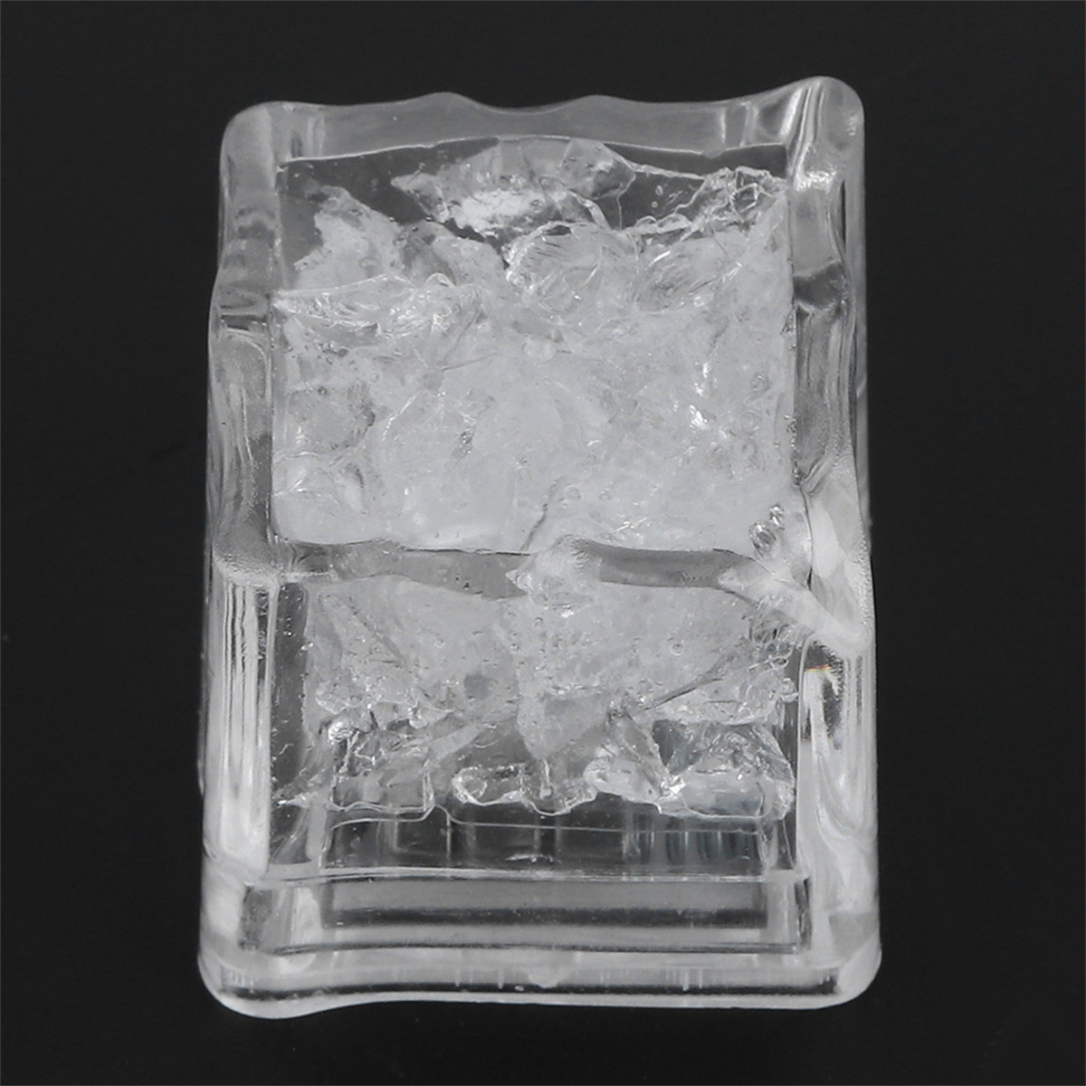 Transparenter Eiswürfelhalter gefüllt mit Eiswürfeln vor schwarzem Hintergrund.