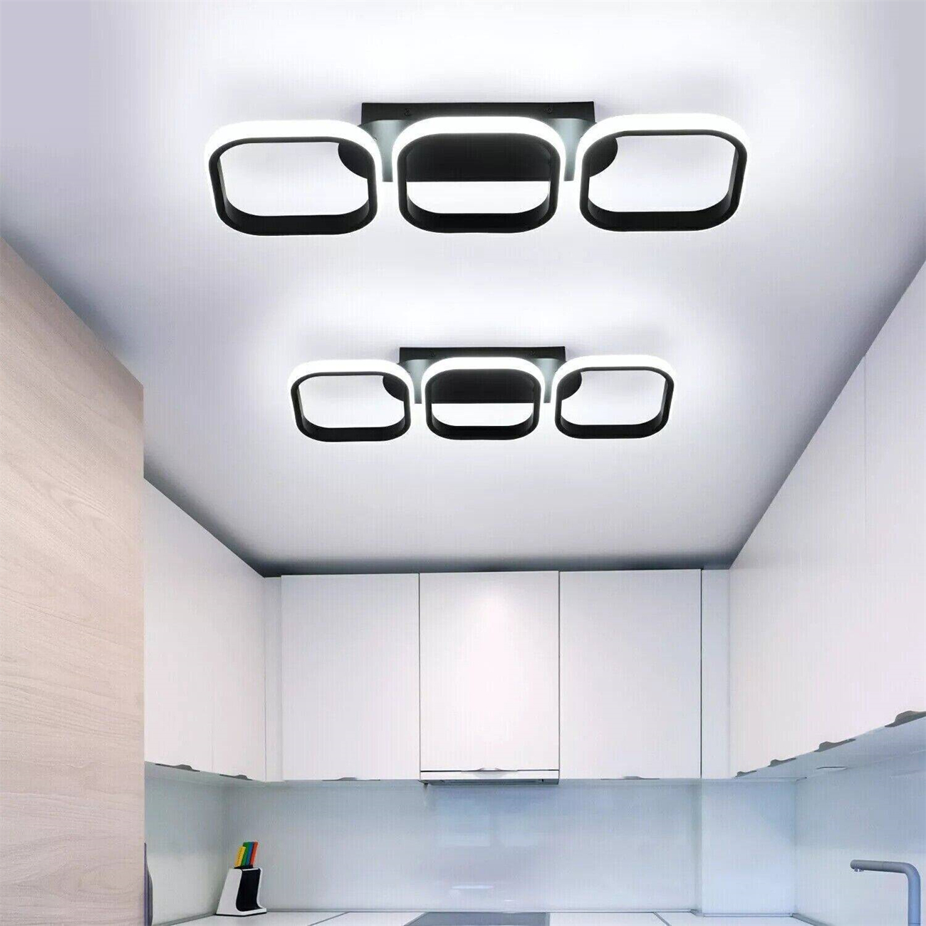 Zwei Sätze von drei schwarzen, quadratisch geformten Lichtern an einer weißen Decke. Die Lichter sind modern und minimalistisch.