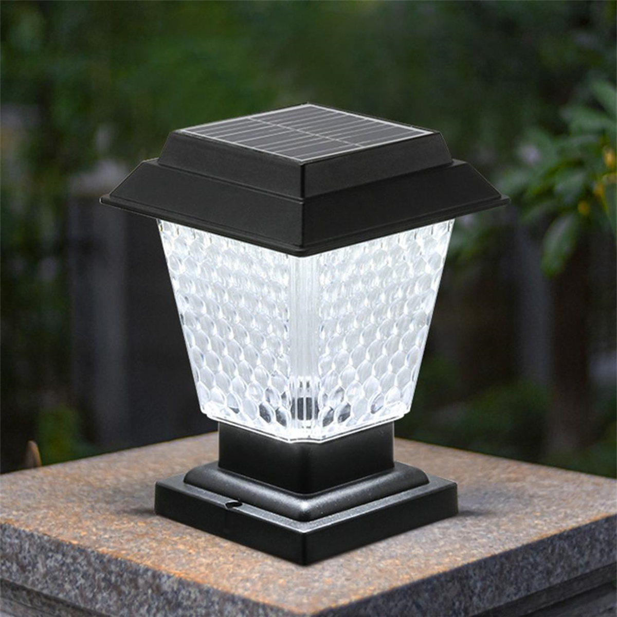 Schwarze Solar-Gartenleuchte auf Stein mit grünem Hintergrund.