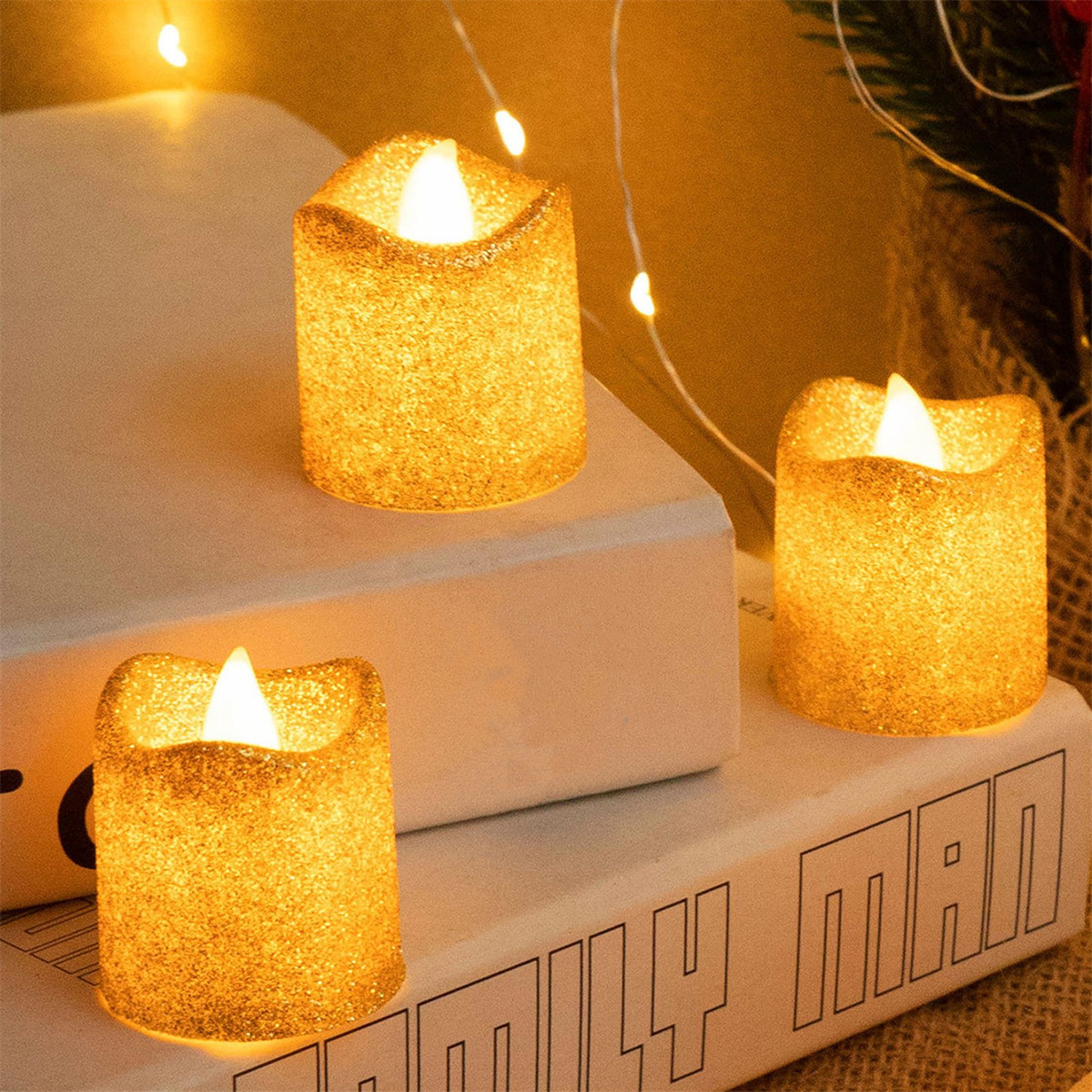 Drei goldene Glitzerkerzen, die auf einem weißen Buch stehen.