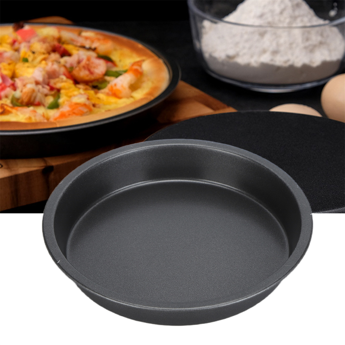 Eine schwarze Pizzaform mit einer Pizza, Zutaten im Hintergrund. Die Pfanne ist leer.