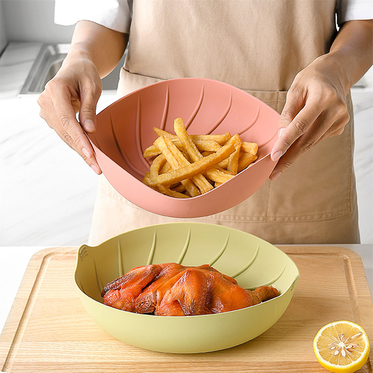 Eine Person hält zwei blattförmige Schalen. Eine enthält Pommes, die andere Hähnchen.