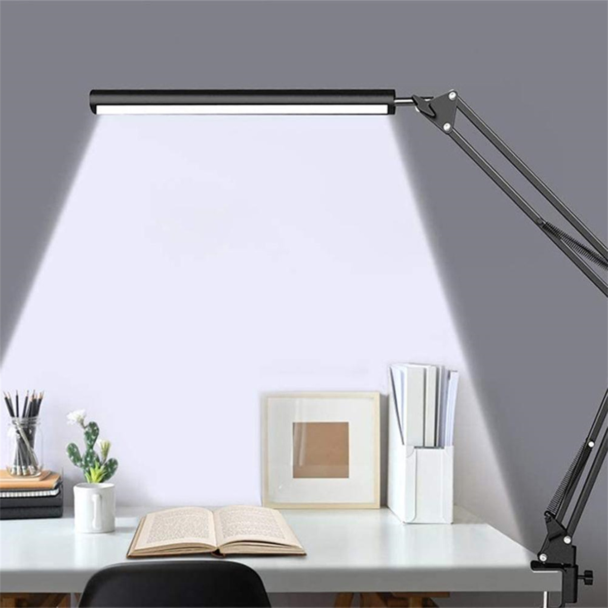 Schwarze Schreibtischlampe, die einen weißen Schreibtisch mit Büchern und Gegenständen beleuchtet.