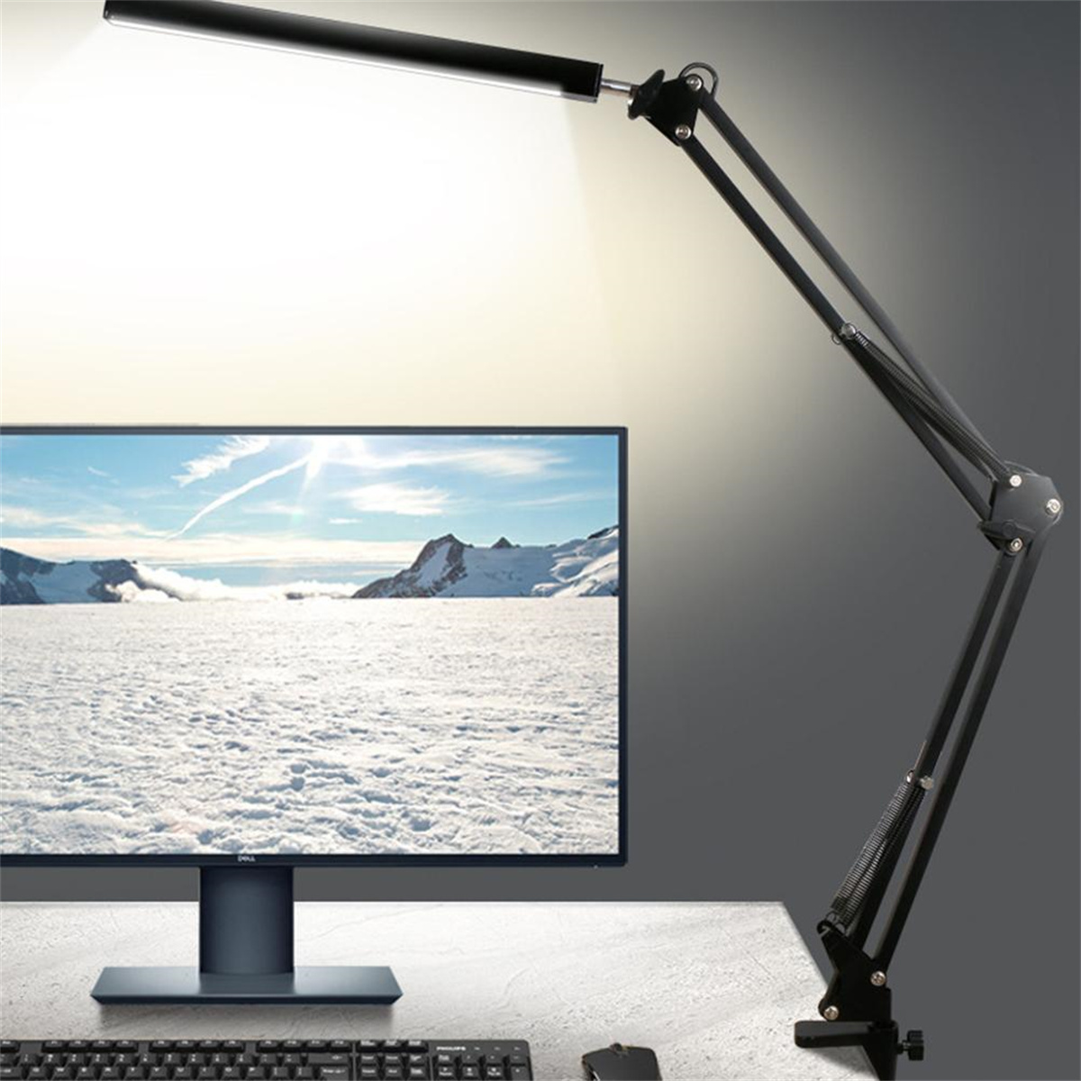 Schwarze Schreibtischlampe über einem Monitor mit einer schneebedeckten Landschaft, mit Tastatur und Maus.