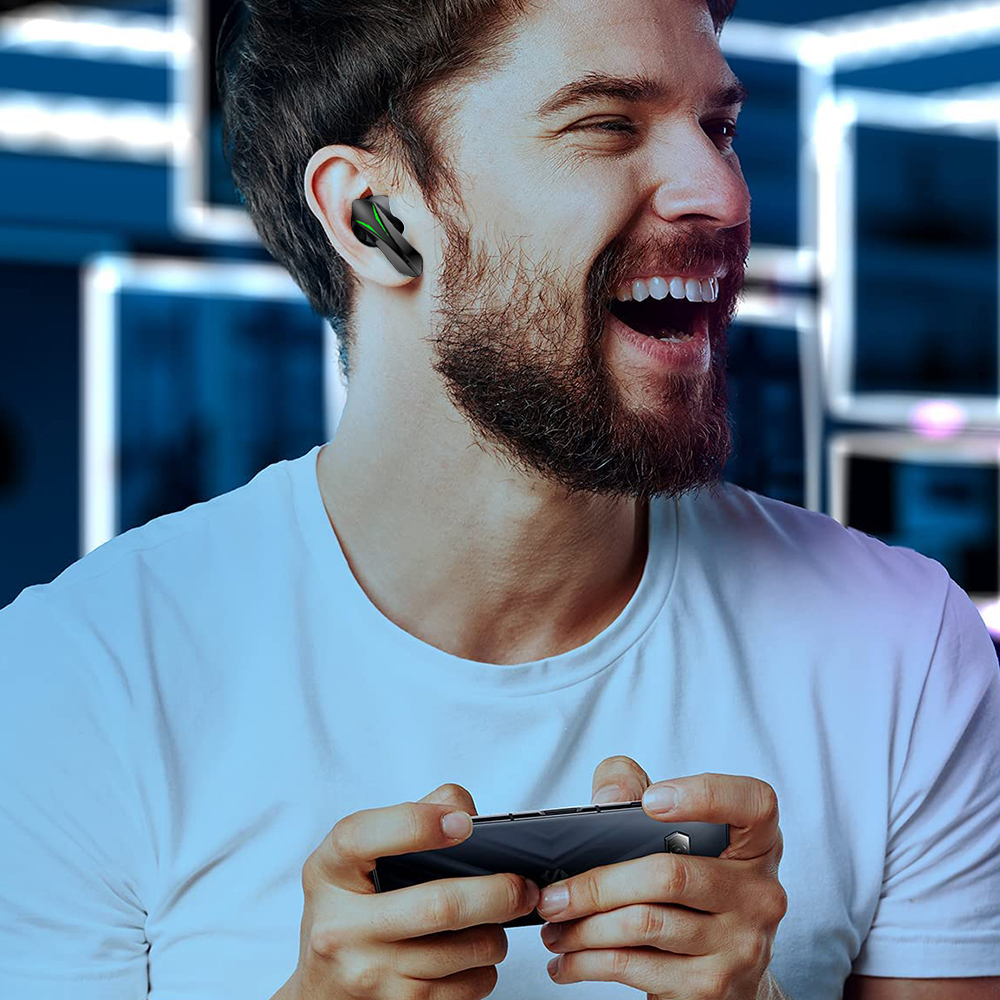 Ein Mann mit Bart lächelt und spielt ein Spiel auf seinem Handy. Er hat Ohrhörer in den Ohren.
