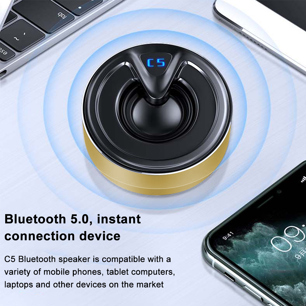 Bluetooth-Lautsprecher, schwarz und gold. Telefon und Tablet sind in der Nähe. Blaues Licht um den Lautsprecher.
