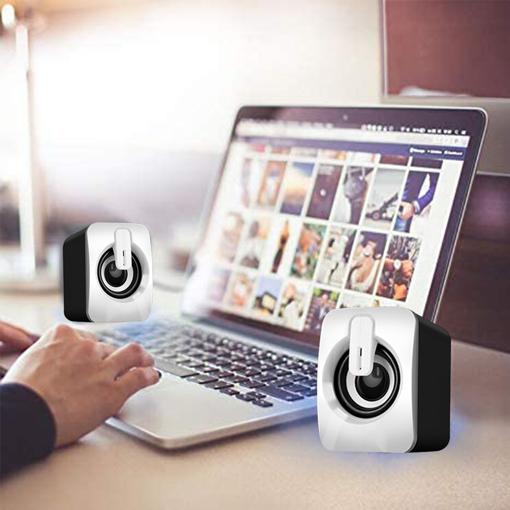 Laptop mit zwei weißen Lautsprechern, Hand einer Person links.