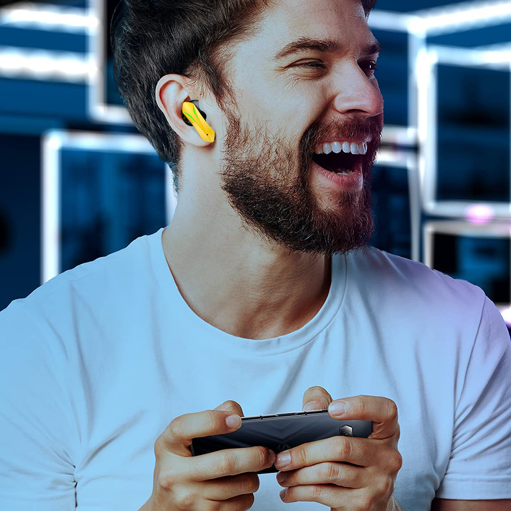Ein Mann lächelt, während er ein Spiel auf seinem Handy mit gelb-schwarzen Kopfhörern spielt.
