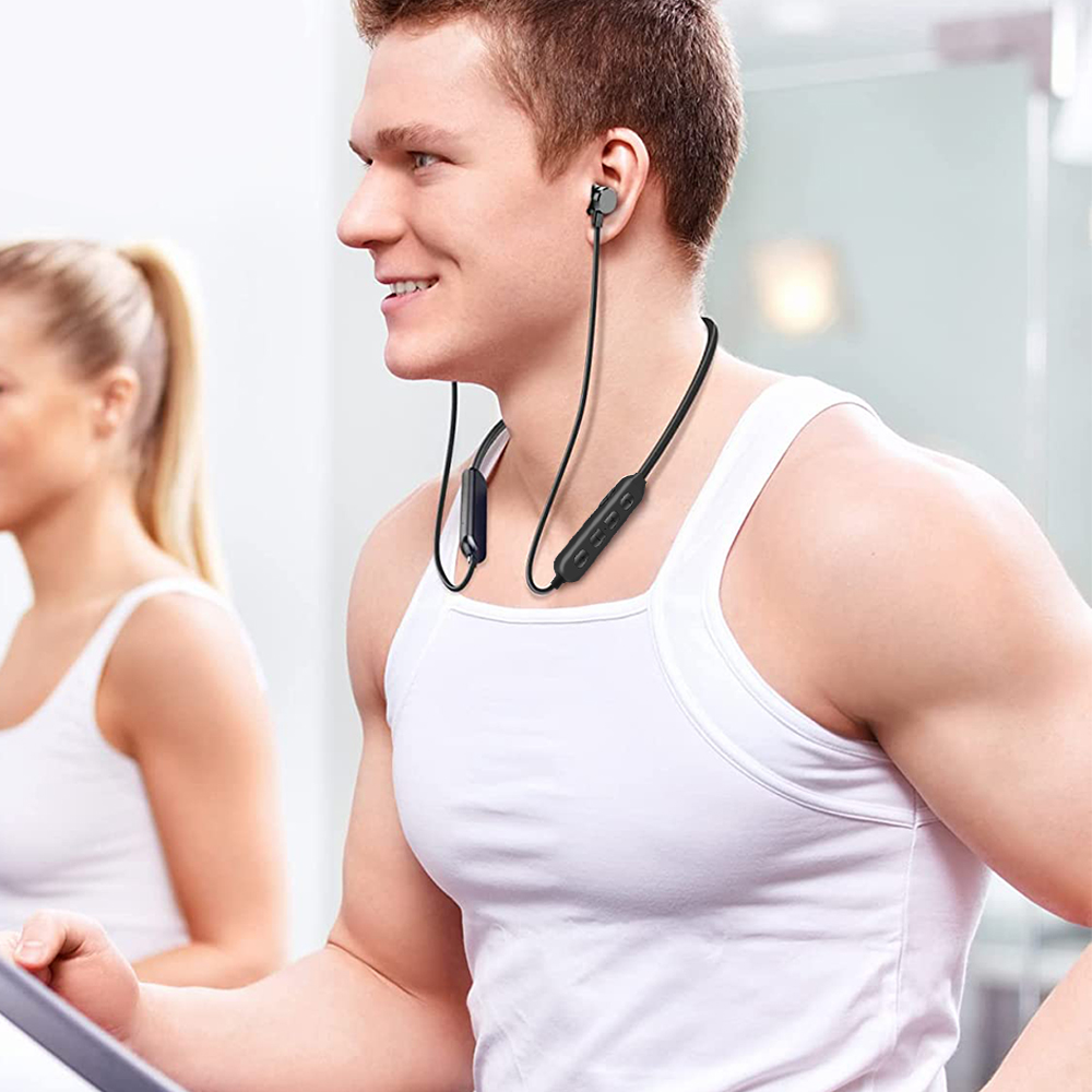 Ein Mann, der ein schwarzes Headset trägt, während er in der Nähe einer Frau in einem Fitnessstudio trainiert.