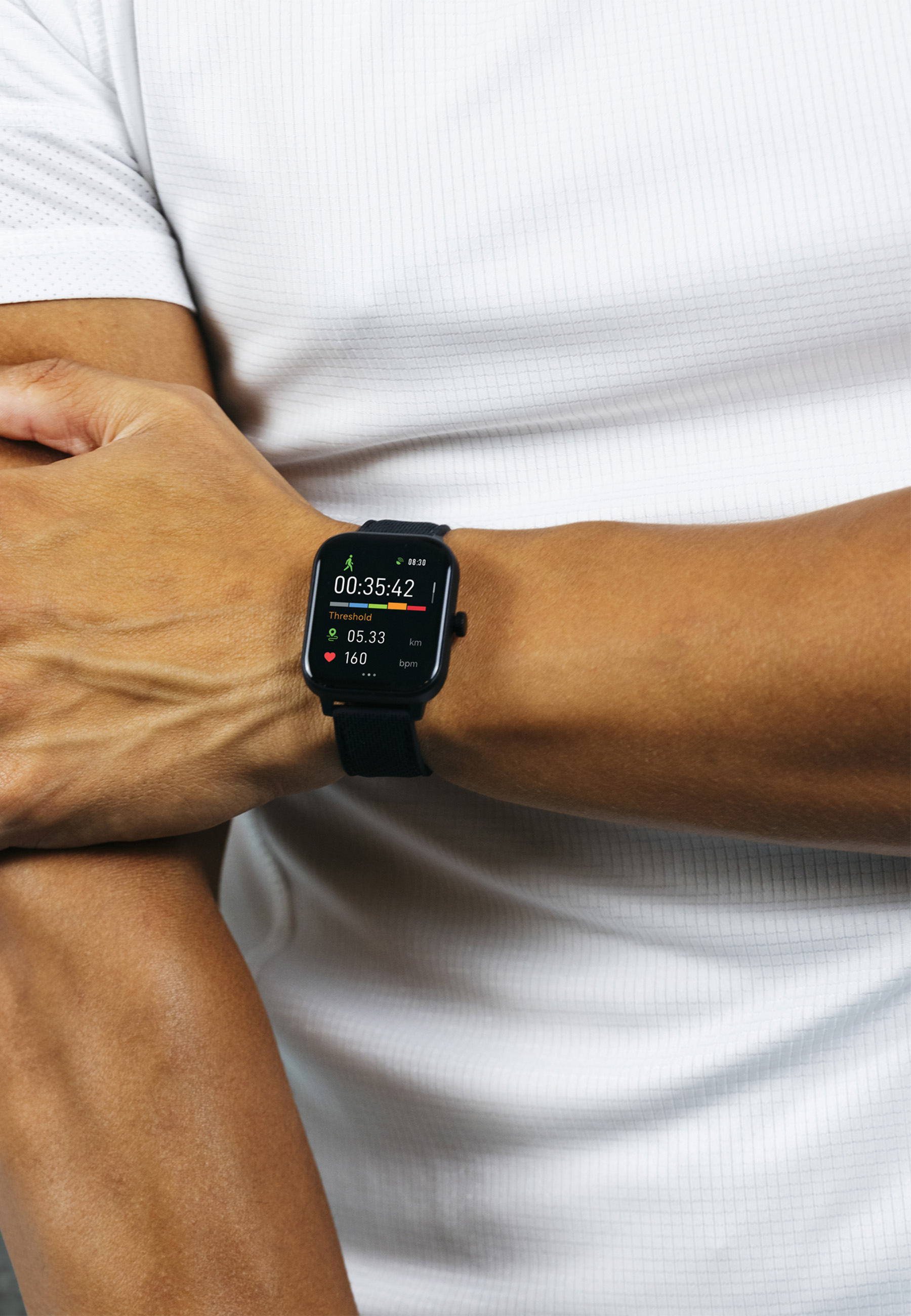 Une montre intelligente noire au poignet, affichant une minuterie, la distance et la fréquence cardiaque.
