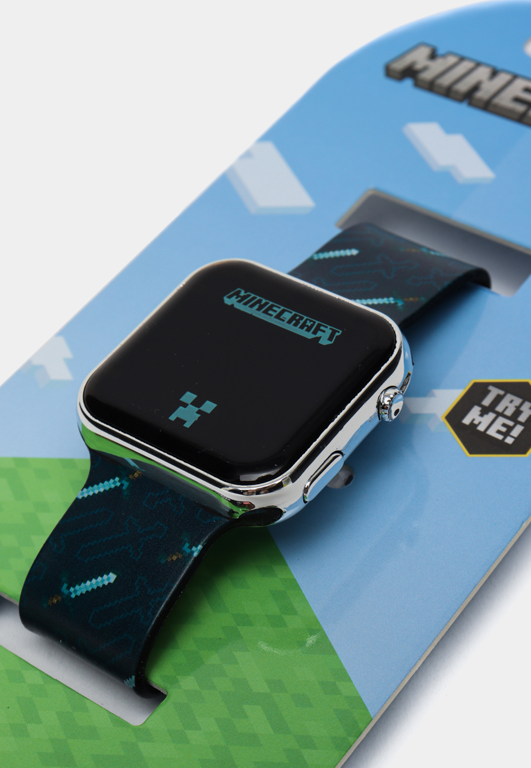 Smartwatch Minecraft sur fond bleu et vert. Écran noir. Affiche le logo du jeu.