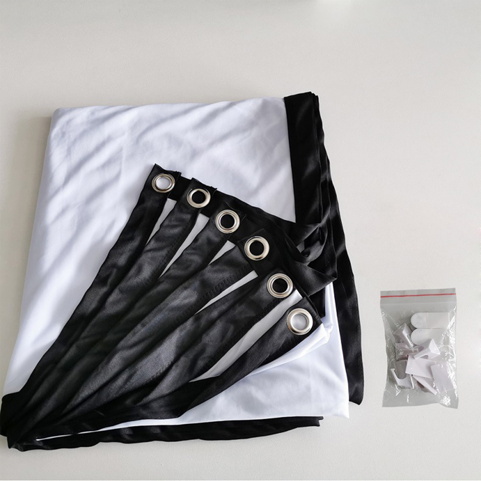 Weiße Projektorleinwand mit schwarzen Rändern und Riemen. Eine kleine Tasche mit Clips.