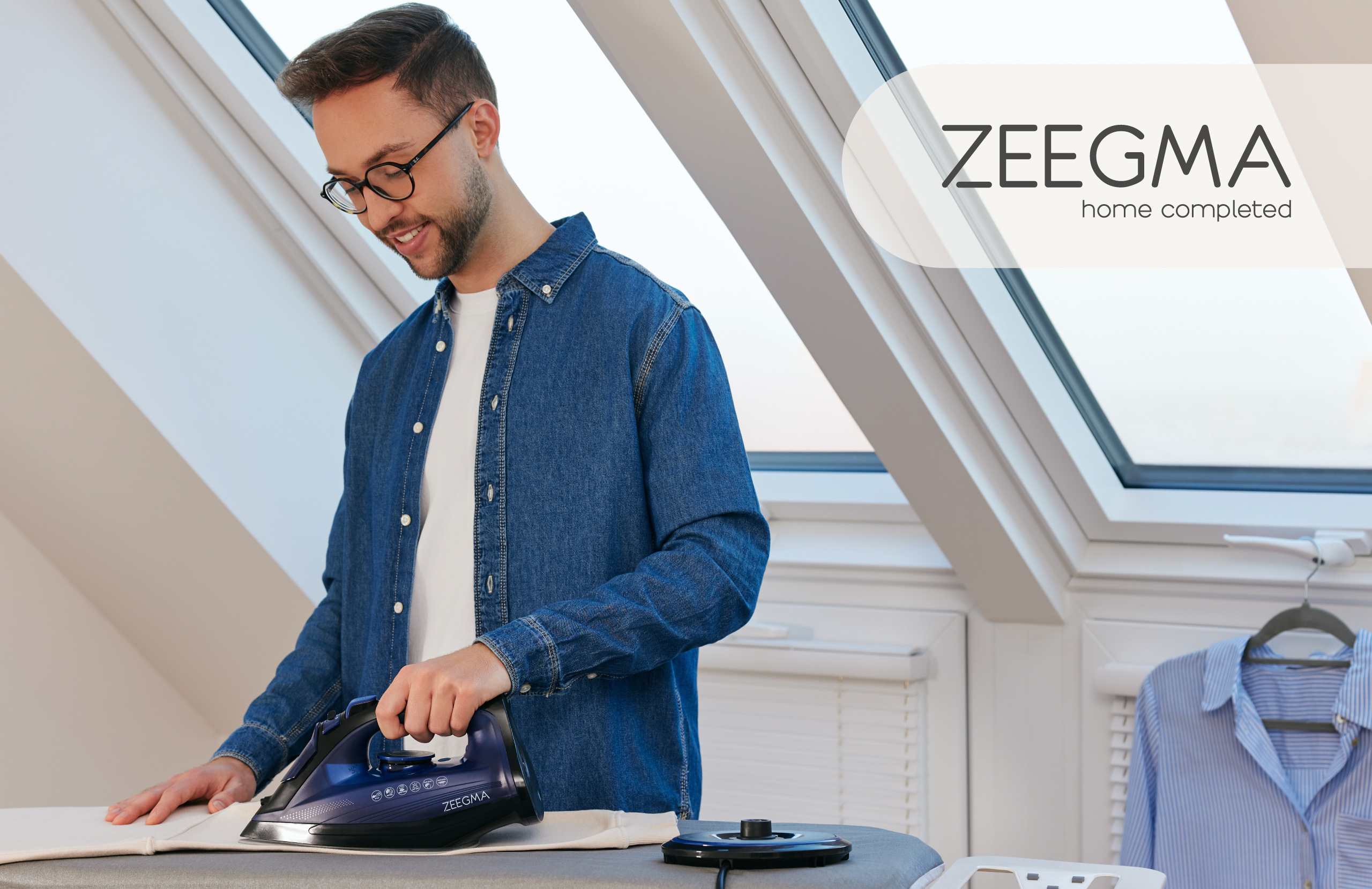 Mann bügelt Kleidung mit ZEEGMA-Bügeleisen, Text rechts. Oberlicht im Hintergrund.