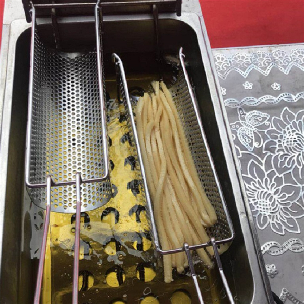 Fritteuse mit zwei Körben, einer mit Pommes gefüllt.