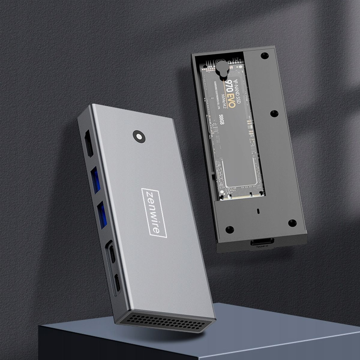 Srebrne urządzenie z portami USB, z czarnym dyskiem SSD. Urządzenie znajduje się na ciemnym tle.