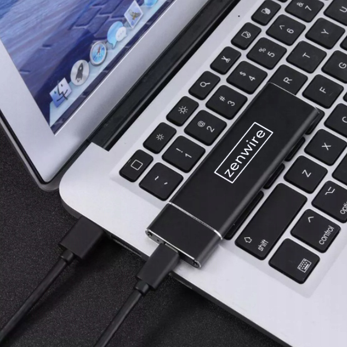 Czarny, prostokątny element jest podłączony do laptopa za pomocą kabla USB. Urządzenie posiada logo.