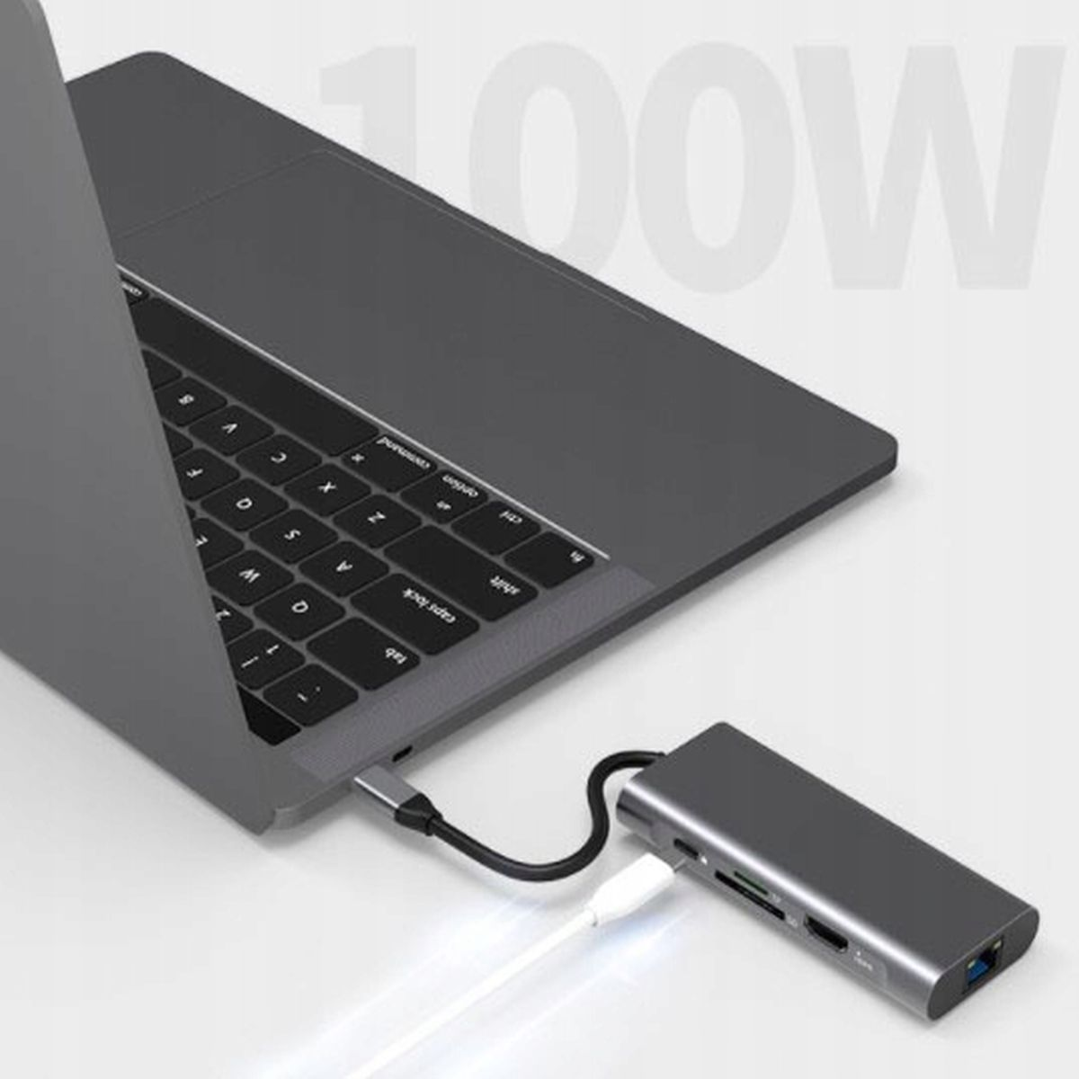Laptop podłączony do srebrnego huba USB z różnymi portami i kablami.