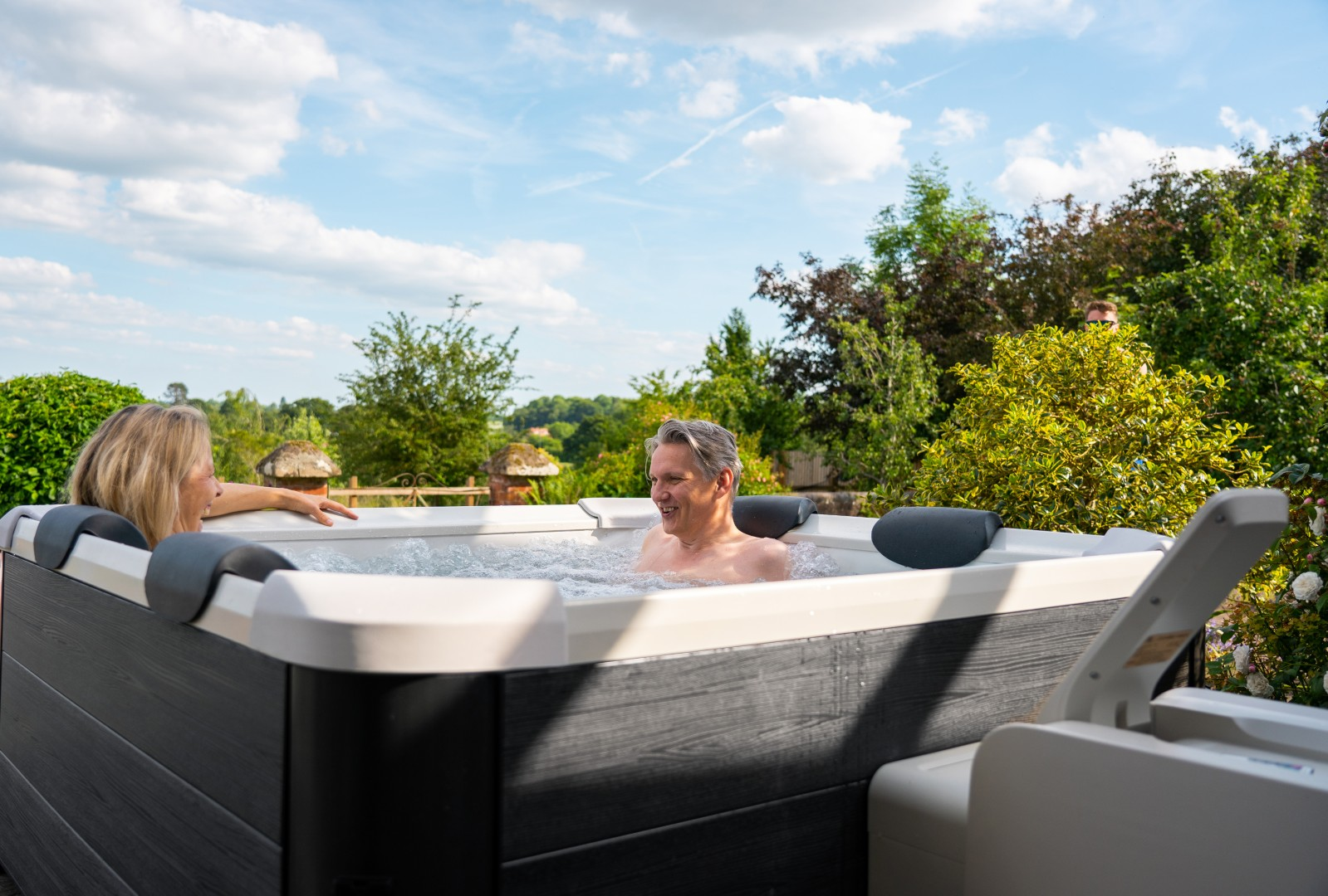 Zwei Personen in einem Whirlpool, die die Natur genießen, mit grünem Hintergrund.