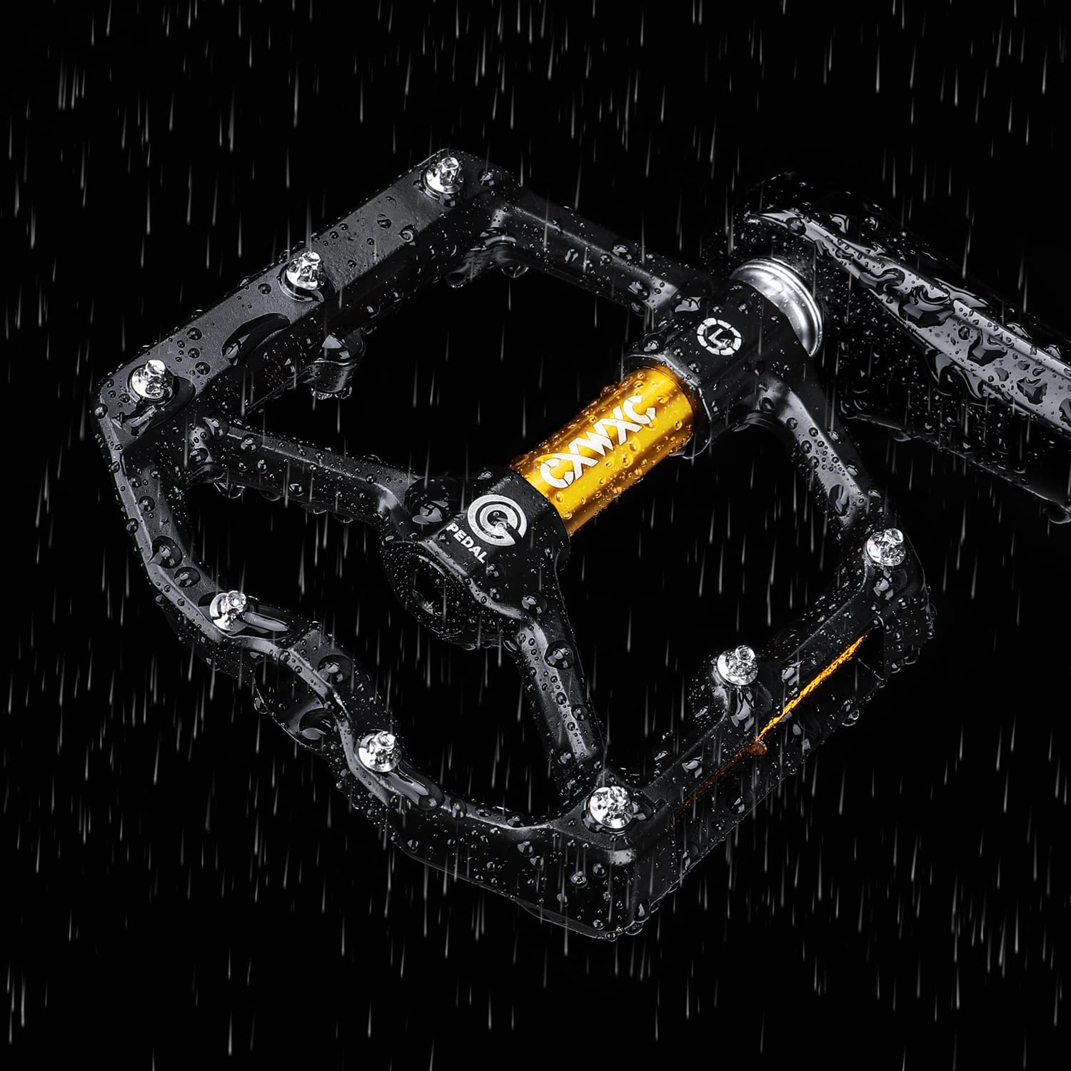 Nahaufnahme eines schwarzen Fahrradpedals mit Wassertropfen. Das Pedal hat einen Metallrahmen mit einer goldfarbenen Mittelachse.
