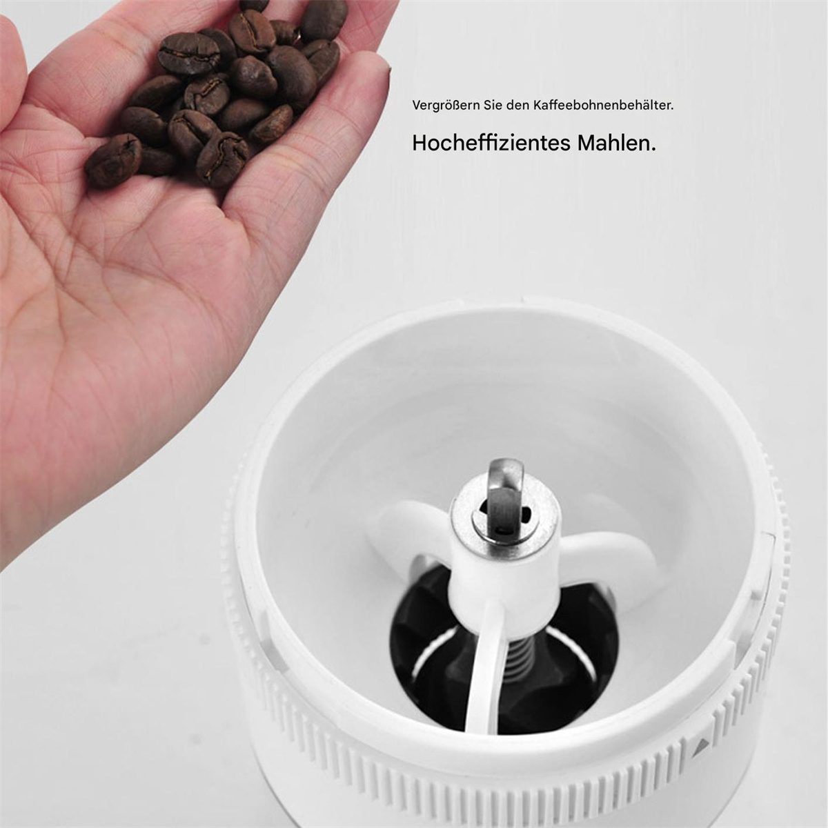Hand hält Kaffeebohnen über einem weißen Kaffeemahlwerk. Die Mühle ist weiß.