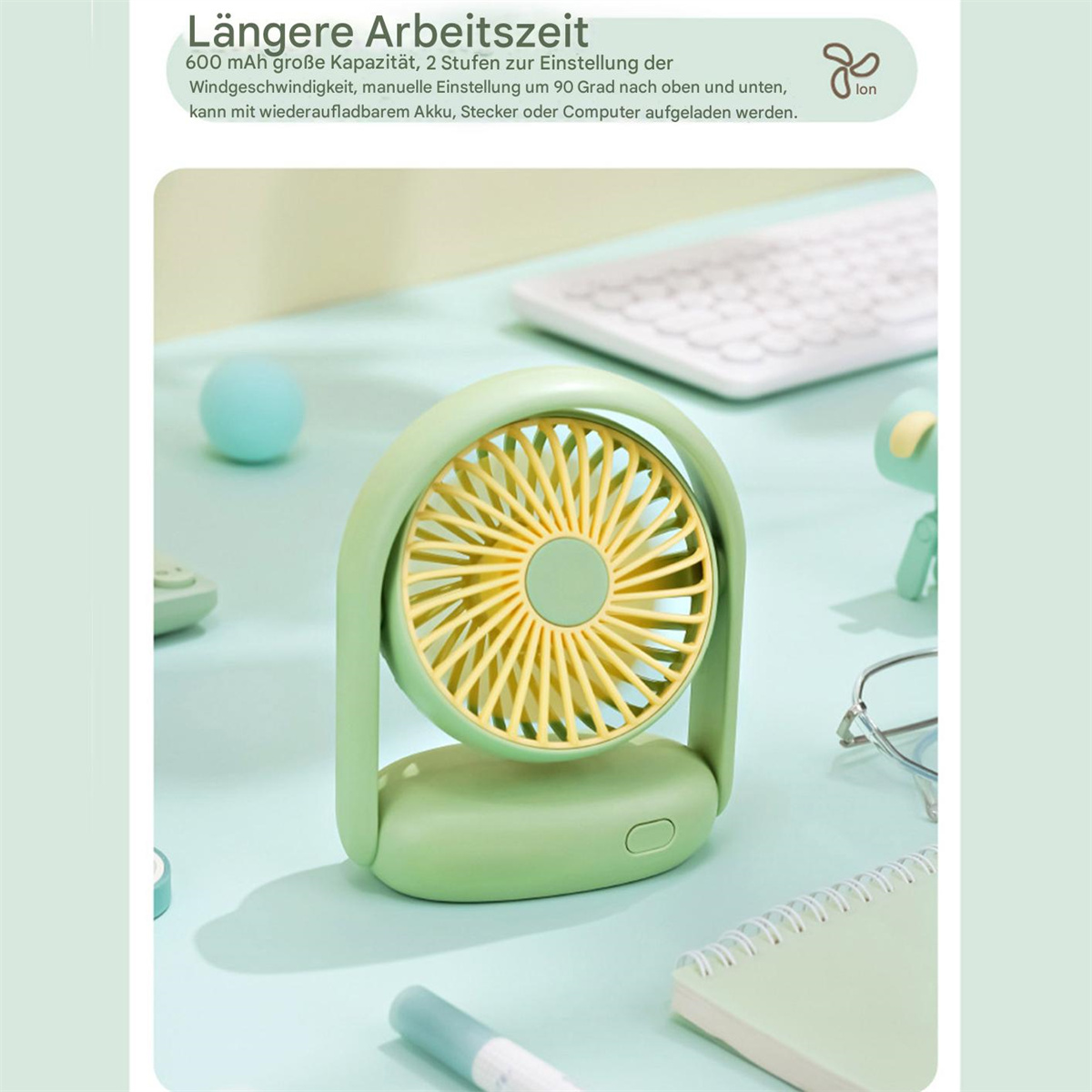 Grüner Ventilator mit gelbem Lüfterrad, auf einem Schreibtisch mit weißer Tastatur und anderen Gegenständen.