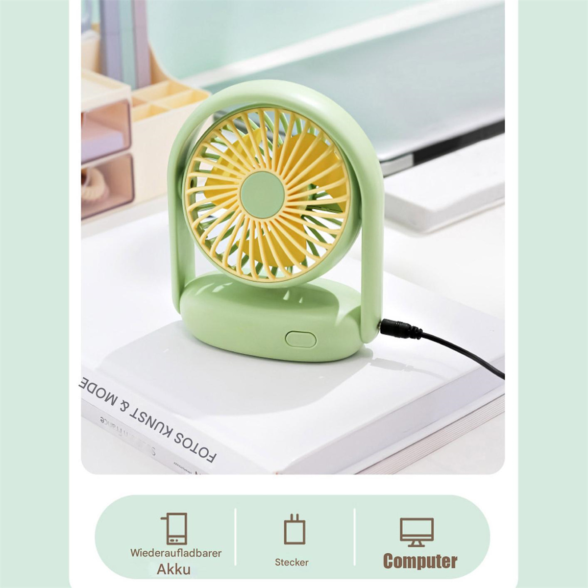 Grüner Mini-Ventilator auf einem Buch mit Computer-, Stecker- und Akku-Symbolen.
