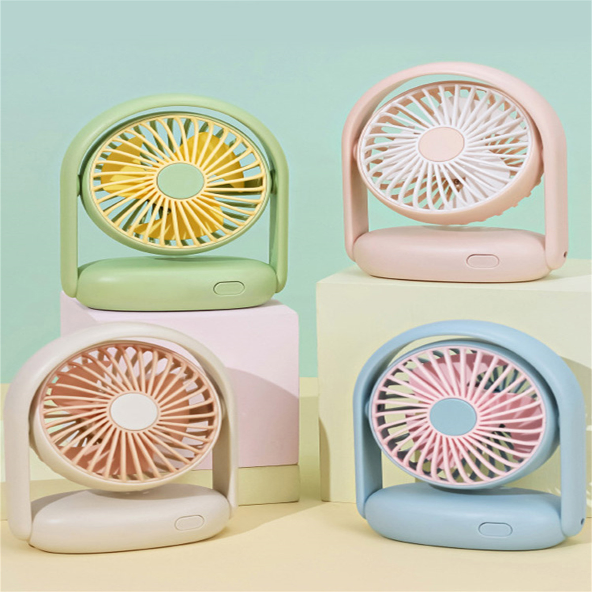 Vier bunte Mini-Ventilatoren auf Sockeln. Grün, Rosa, Pfirsich und Blau, jeder mit anderer Farbe.
