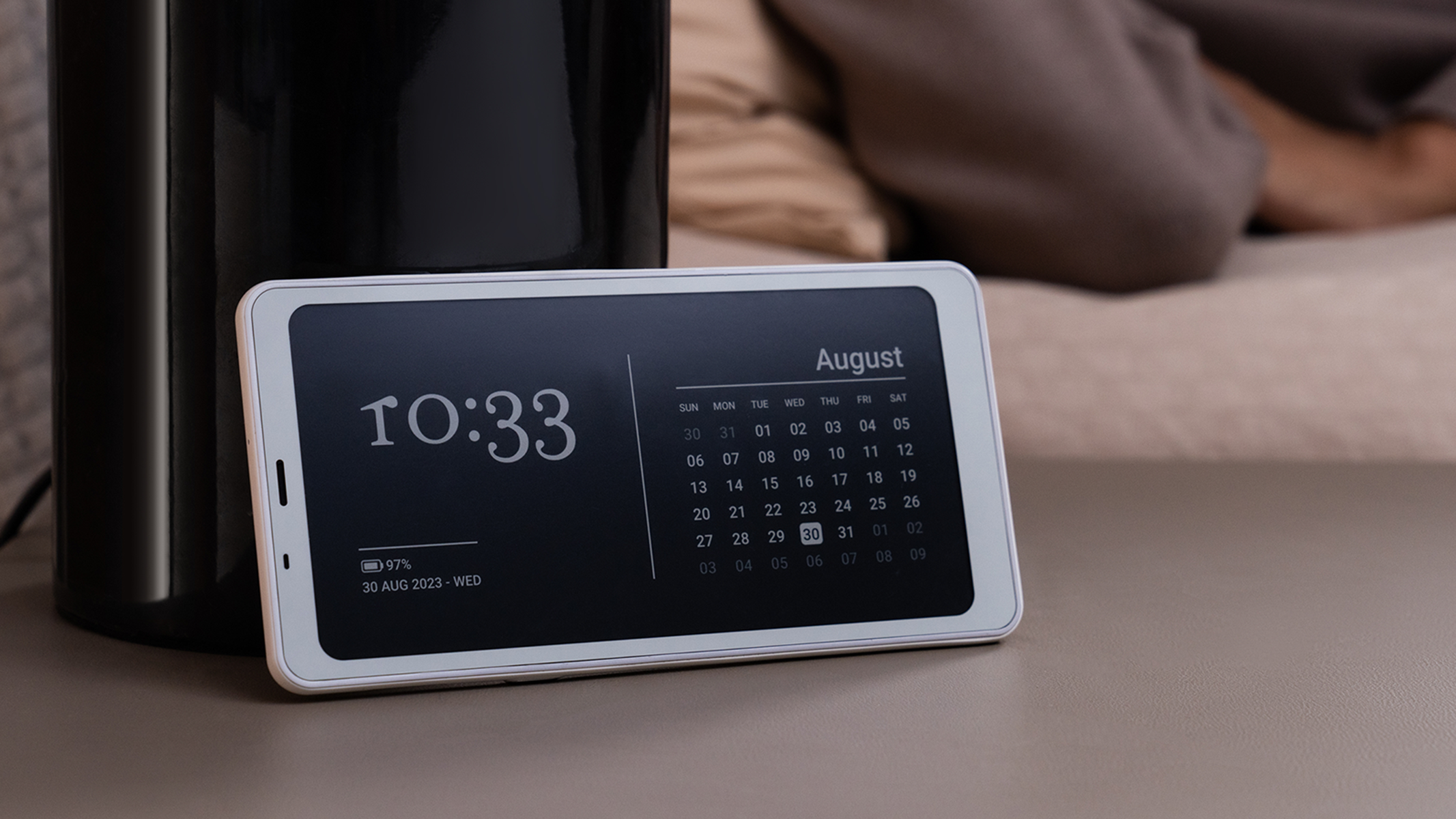 Zegar cyfrowy wyświetlający 10:33 i kalendarz na sierpień 2023. Czarny ekspres do kawy w tle.