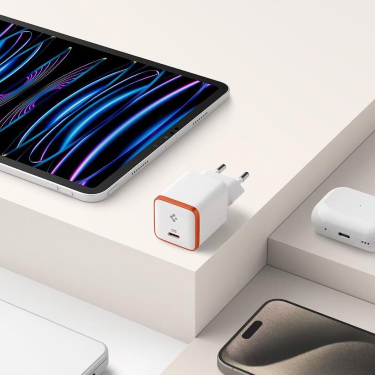 Oplader en apparaten op een wit oppervlak, waaronder een tablet en een smartphone.