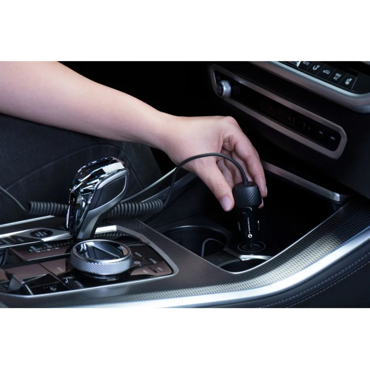 La mano di una persona che collega un caricatore per auto alla console dell'auto.