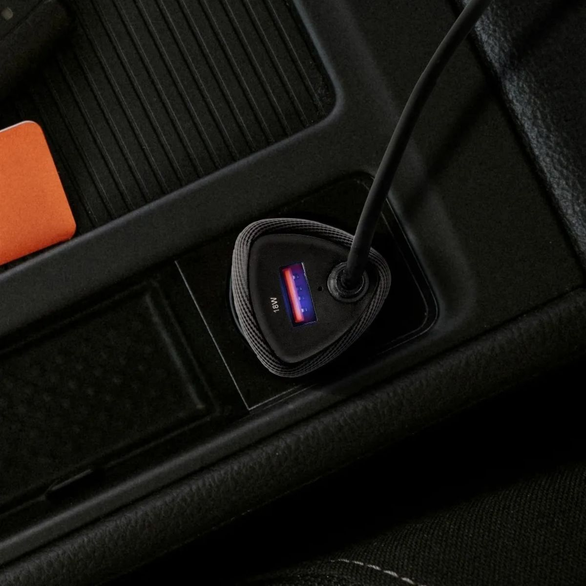 Caricatore per auto nero collegato alla console dell'auto. Ha un indicatore da 18W.