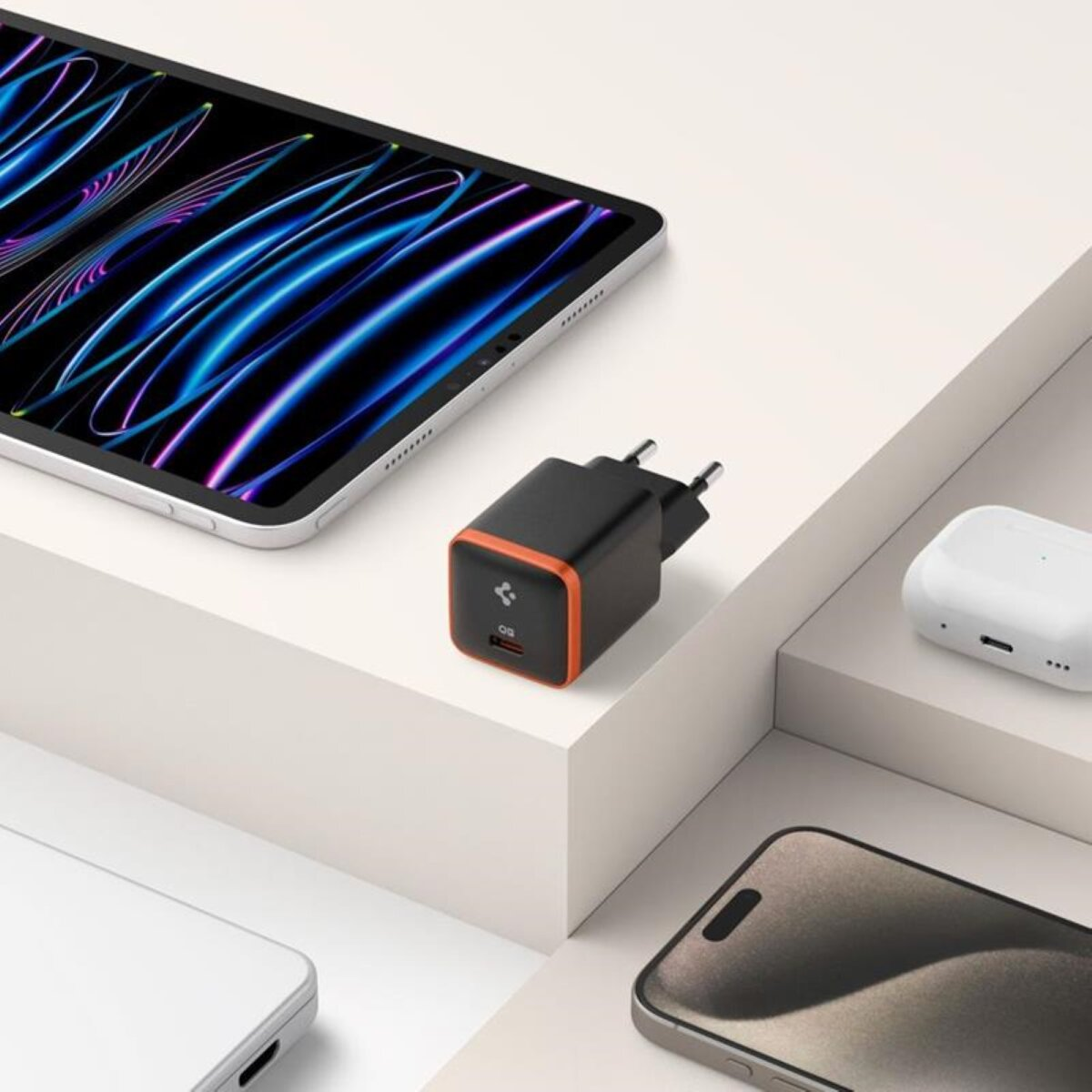 Tablet, oplader en AirPods op een wit oppervlak. De achtergrond heeft witte treden.