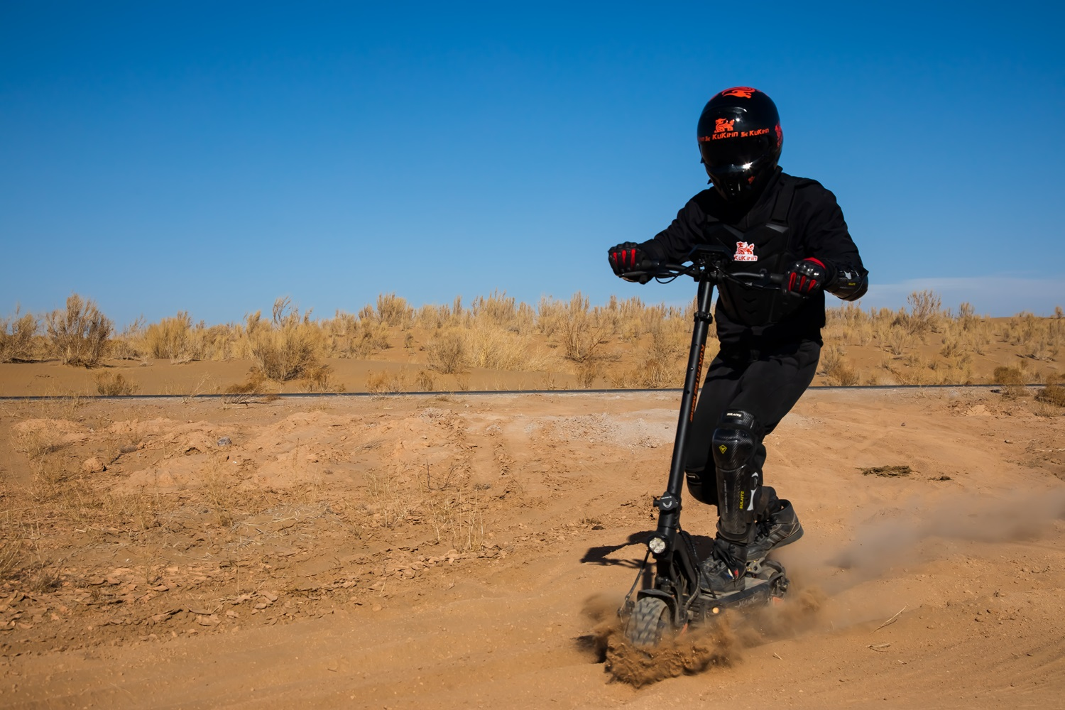 Persona che guida uno scooter elettrico su una strada sterrata, sollevando polvere.