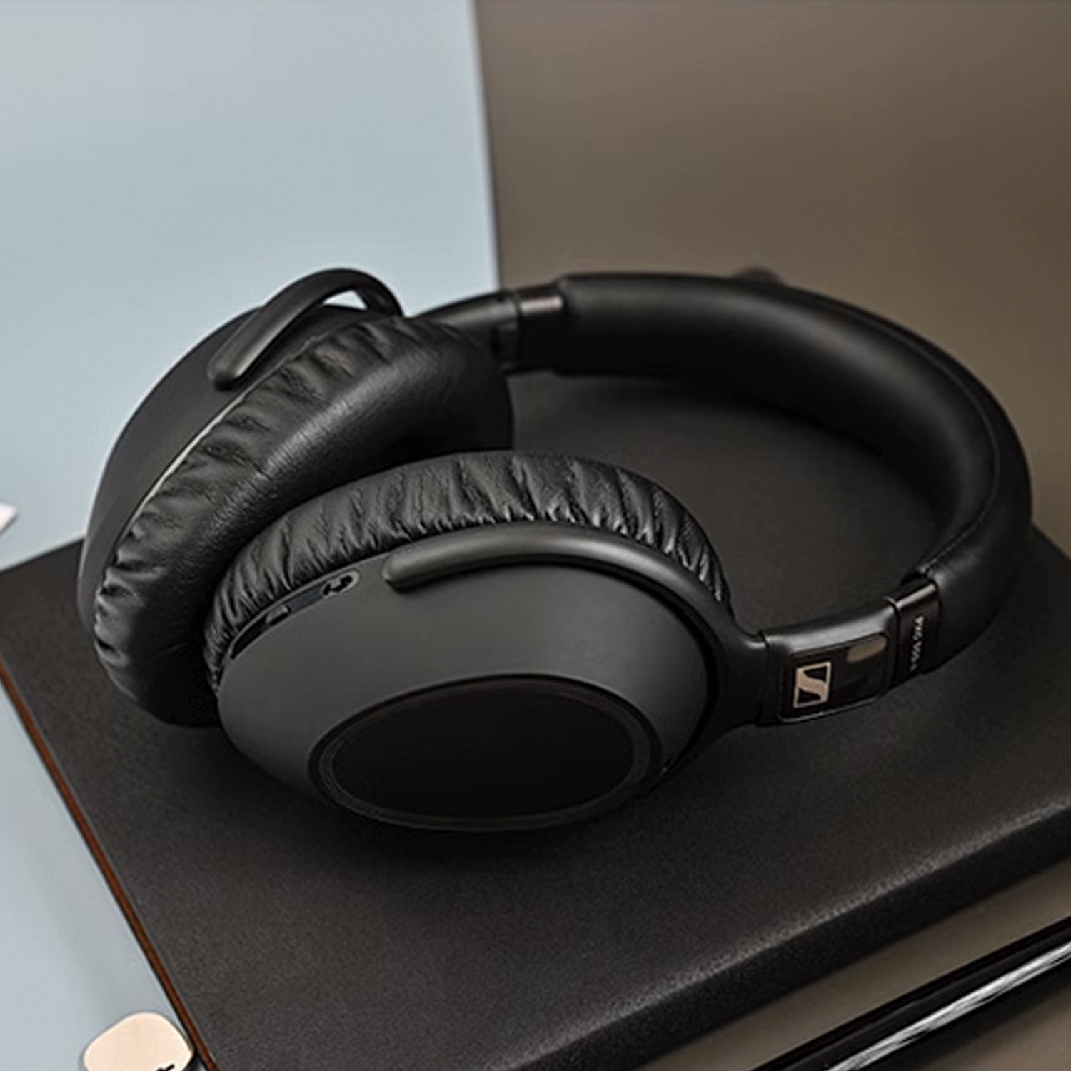Zwarte over-ear koptelefoon op een donkere ondergrond. De koptelefoon heeft grote oorschelpen. De achtergrond is donker en neutraal.