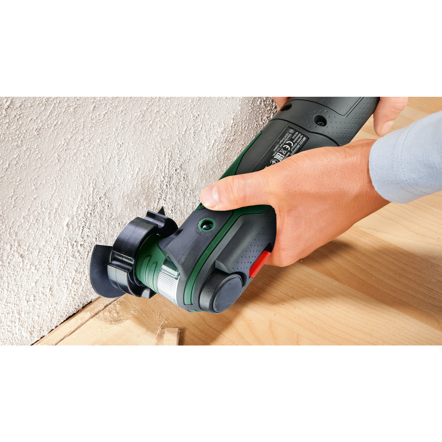 Eine Person, die ein Elektrowerkzeug an einer Wand verwendet. Das Werkzeug schneidet eine Nut in das Holz.