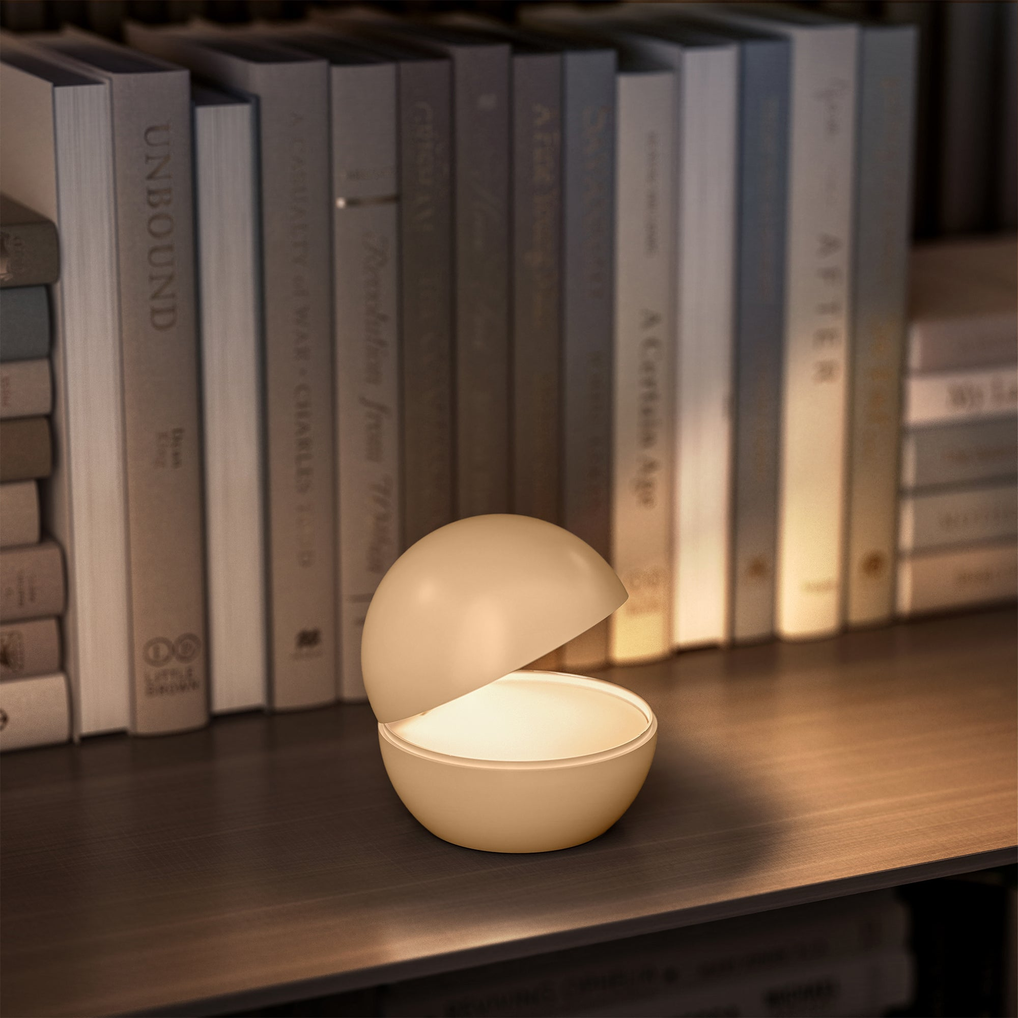 Eine kleine beige Lampe, geformt wie eine Kugel mit Licht von innen, auf einem Regal.