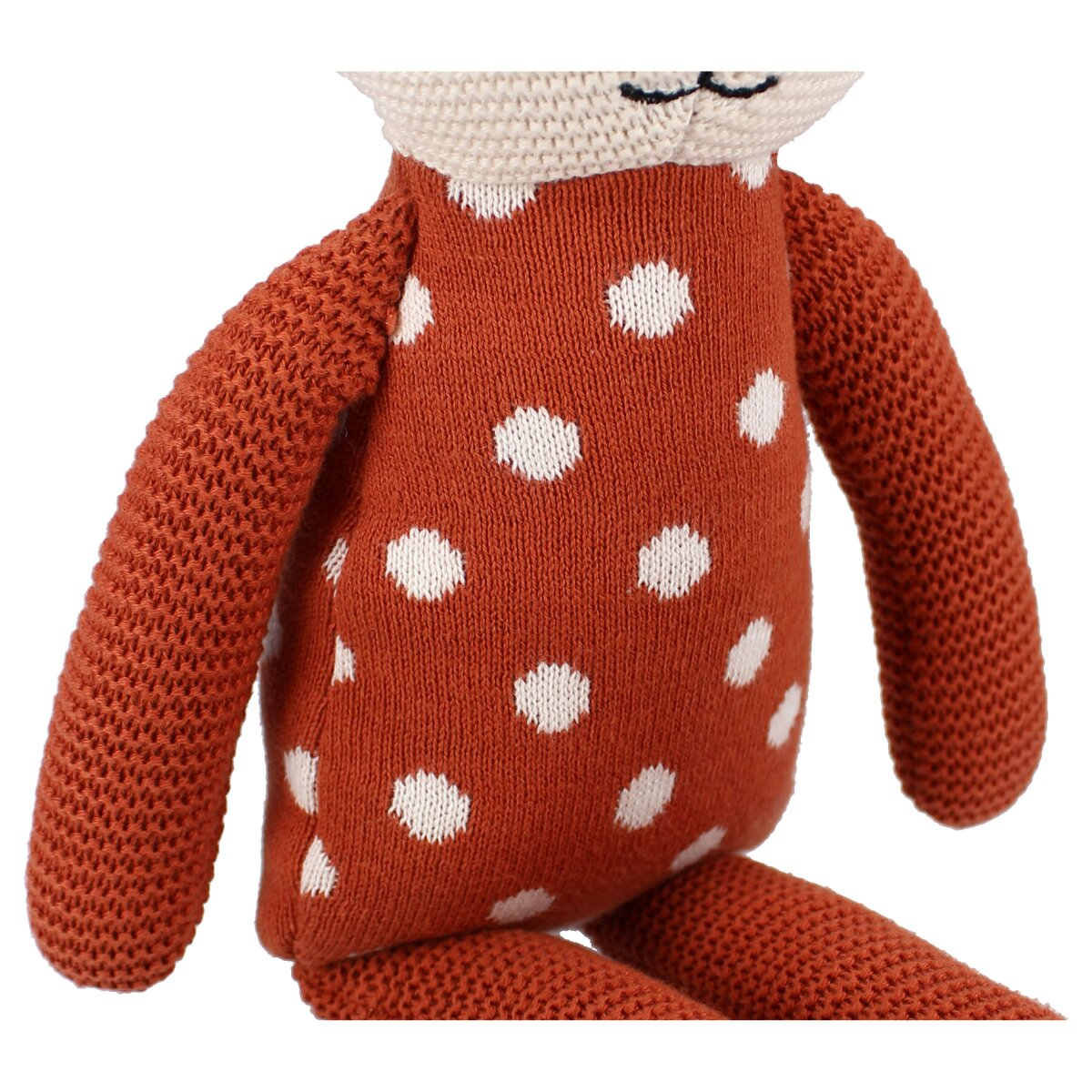 Eine Stoffpuppe mit orangefarbenen Punkten. Die Puppe hat ein cremefarbenes Gesicht und einen Hals.