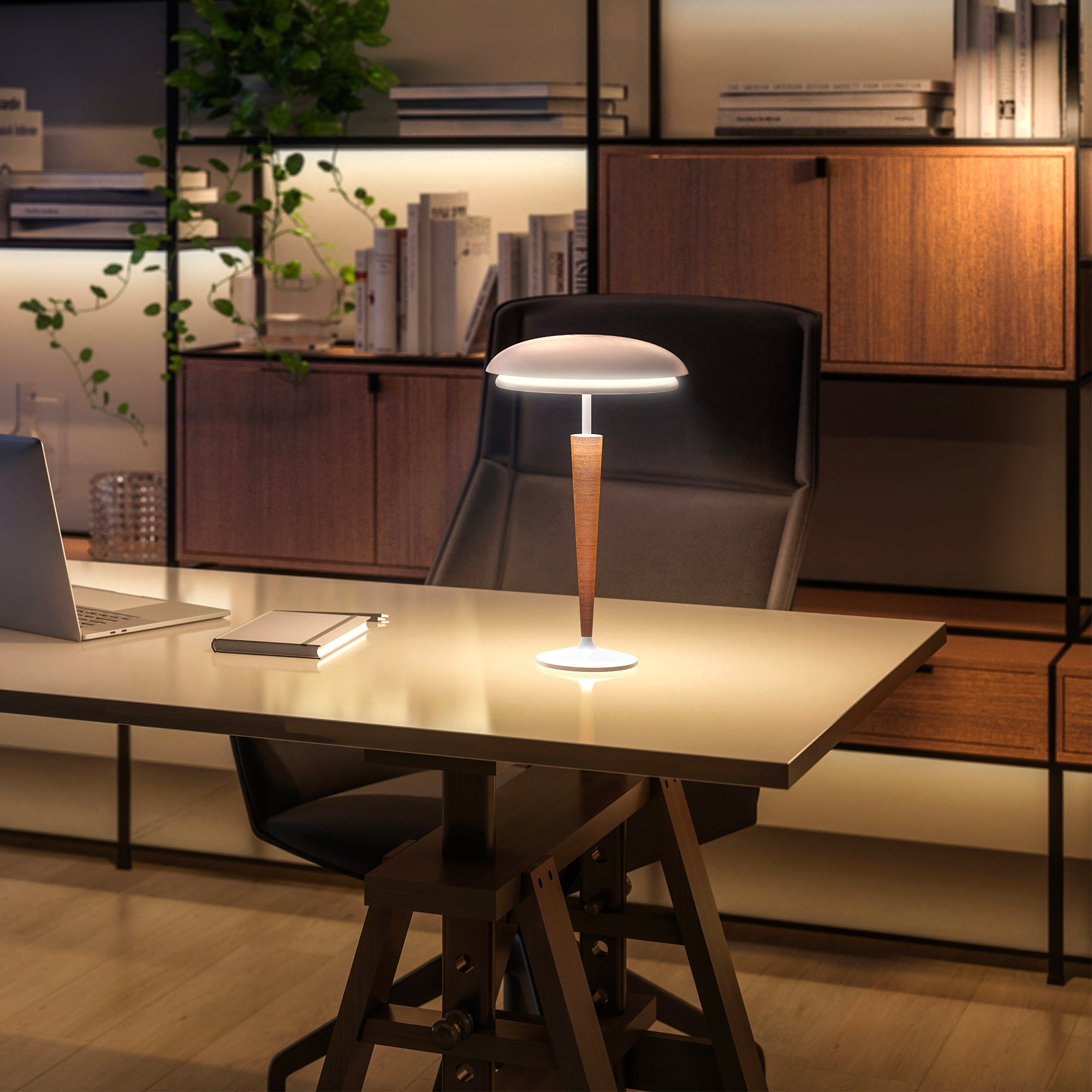 Eine moderne Schreibtischlampe mit Holzstiel und weißem Schirm, die auf einem Schreibtisch in einem gut beleuchteten Büro steht.