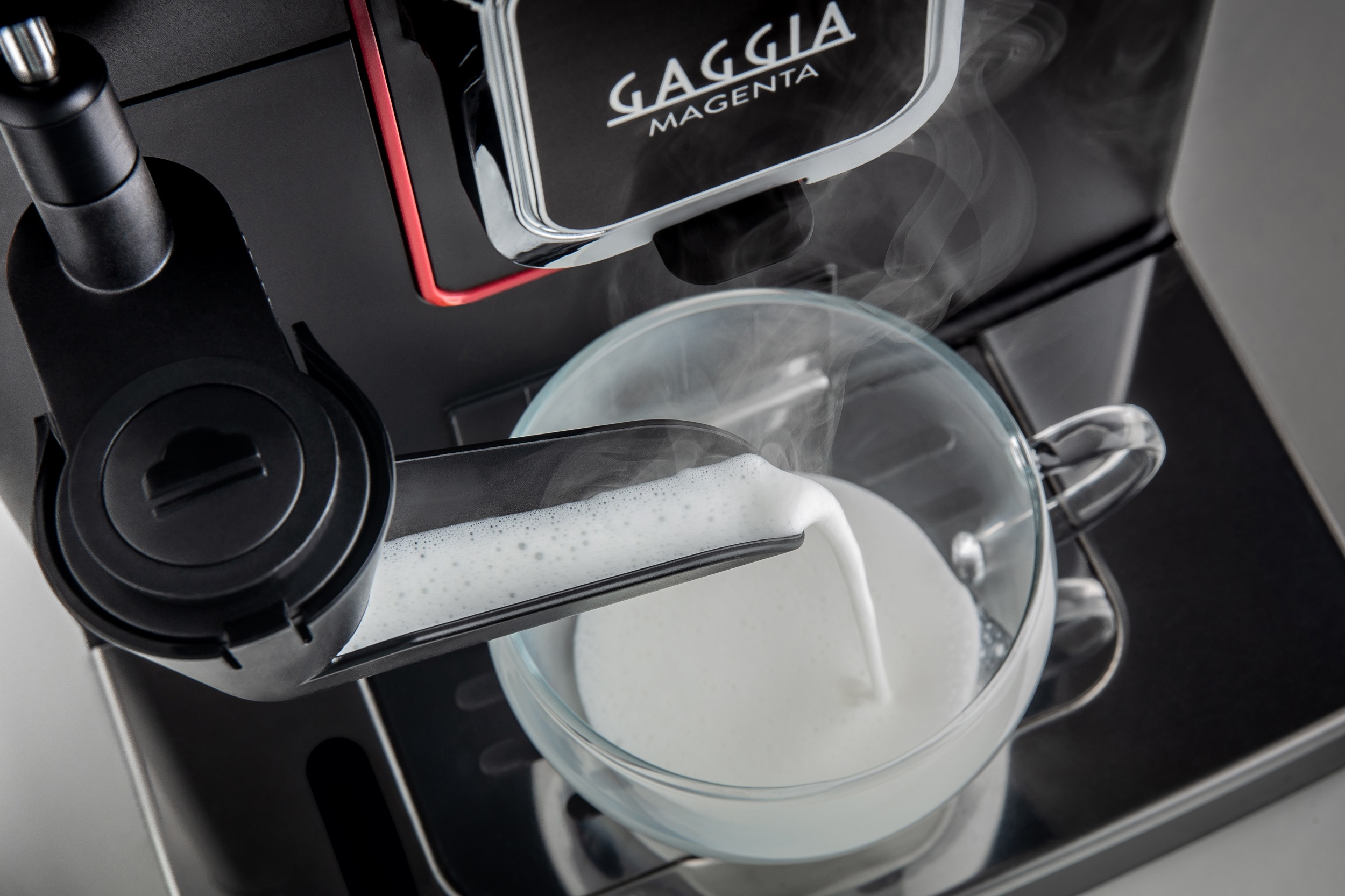 Eine Kaffeemaschine, bei der eine Tasse mit Milchschaum gefüllt wird. Der Markenname 'Gaggia Magenta' ist sichtbar.