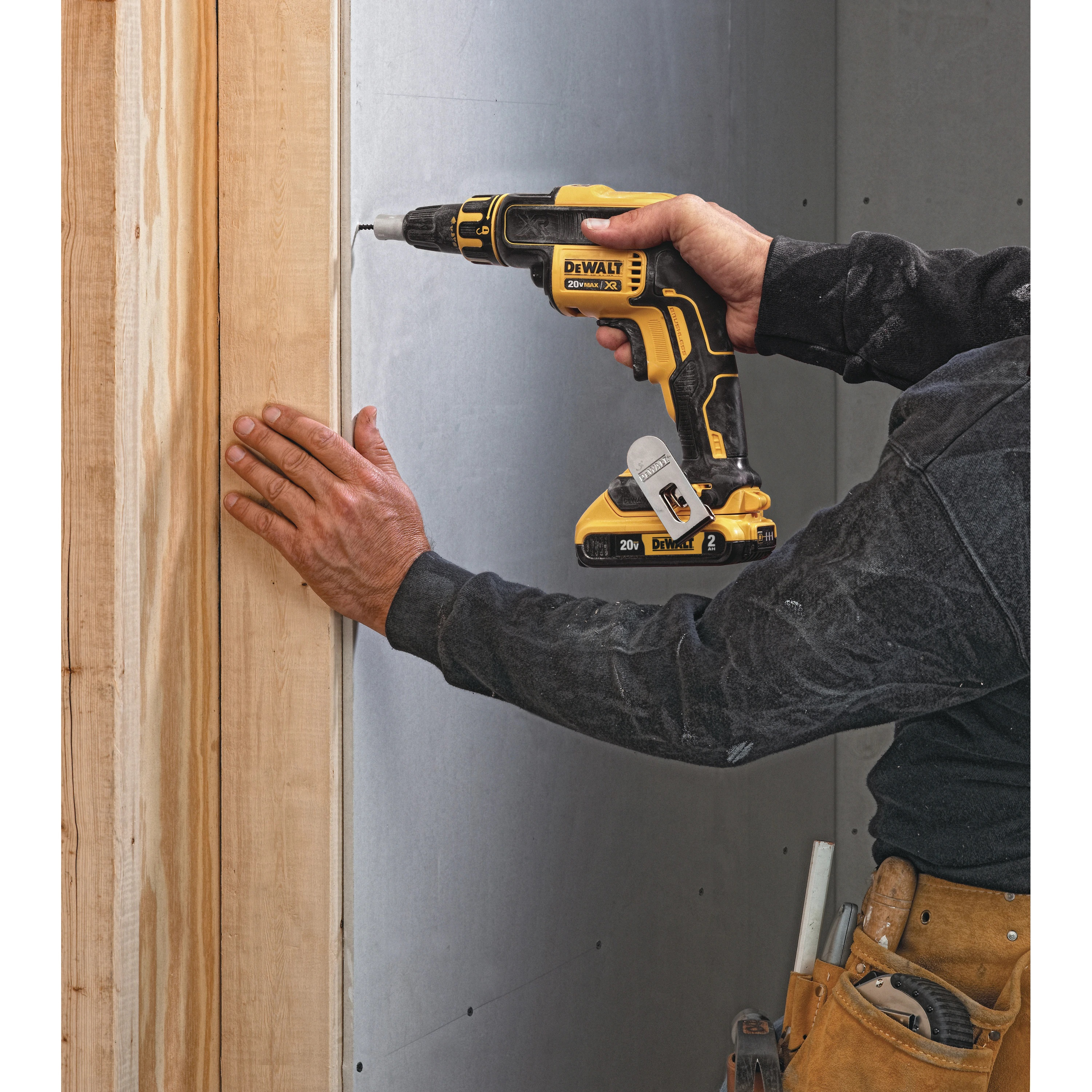 Una persona usa un taladro amarillo y negro para atornillar un montante de madera.